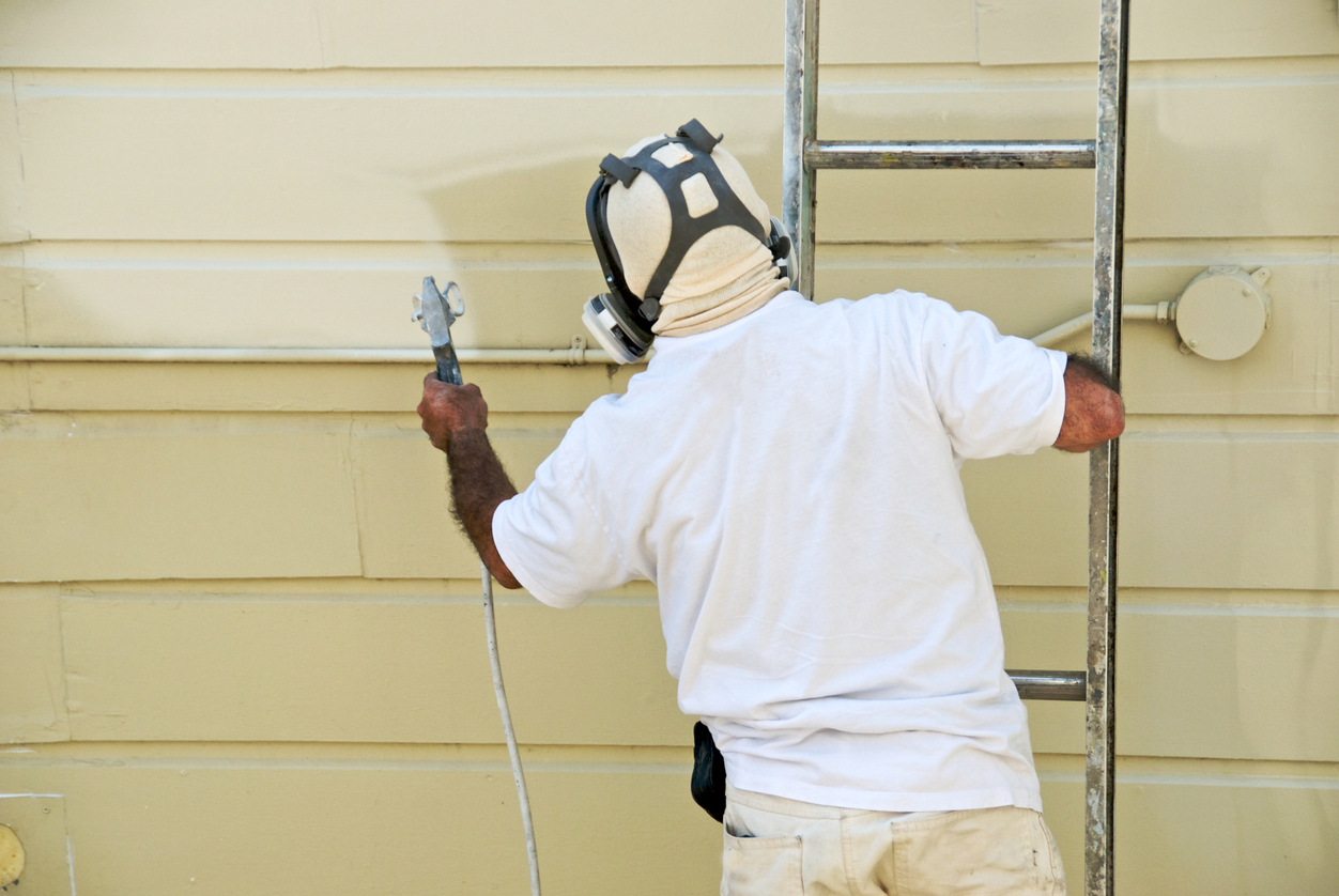 Painting the exterior of a house with spray gun in San Jose