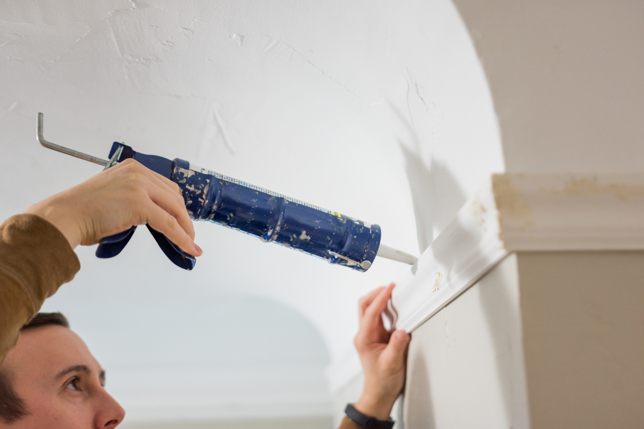 Professional painter uses caulk gun to seal trim in a San Jose home