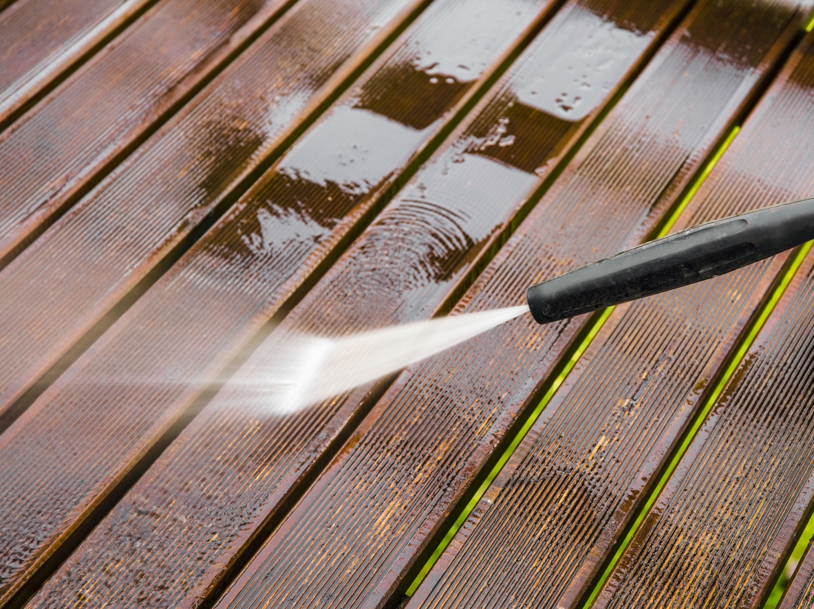 Close up view of using pressure washer to clean impregnated wood terrace outdoors in the spring for a Sunol, CA area home.