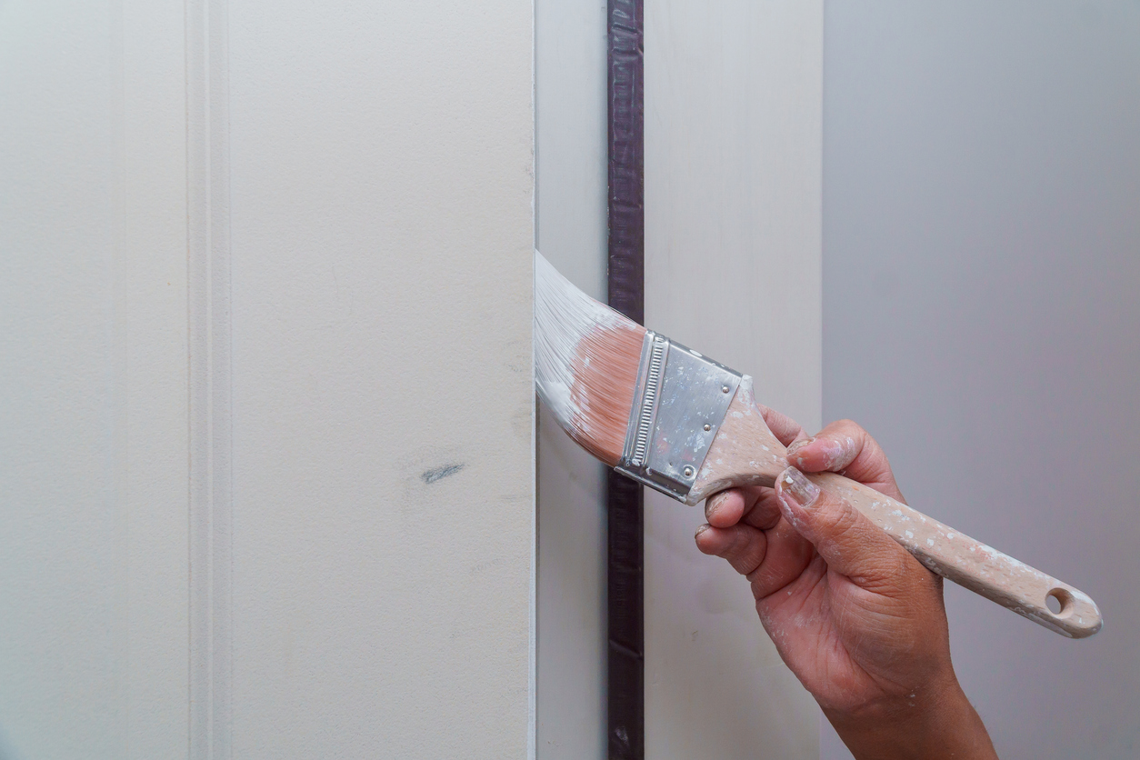 Painting of wooden door, workers hand and brush